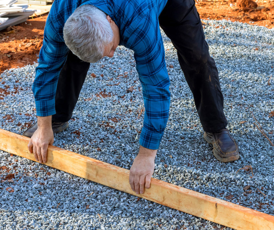 Shed foundation preparation by man with board and gravel